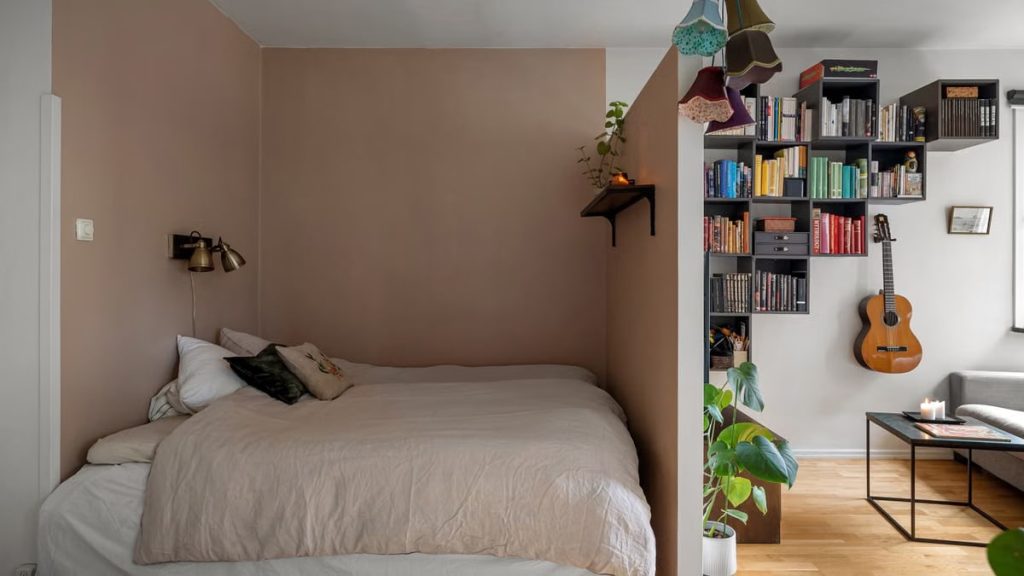A contemporary bedroom with a double bed, guitar, and bookshelf, ideal for a cozy home setting.